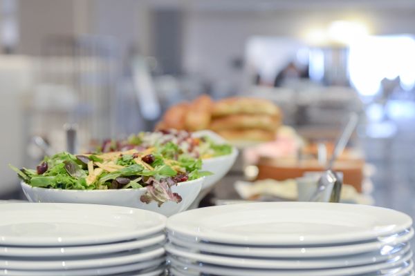 Canteen buffet with plates, salad and pastries