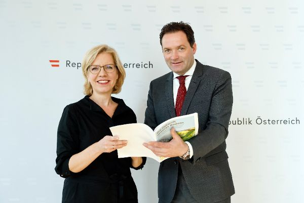 Klimaschutzministerin Eleonore Gewessler und Landwirtschaftsminister Norbert Totschnig halten die Broschüre der Unterrichtsmaterialien für Bodenschutz in der Hand.