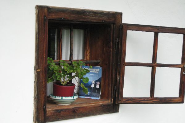 Historisches Doppelkastenfenster mit geöffnetem Außenflügel, auf Fensterbank steht Blumentopf in Keramikübertopf