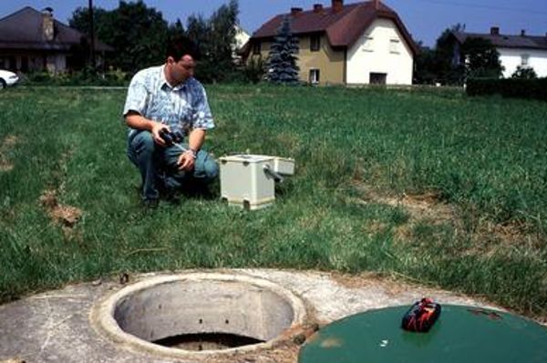 Ein Mann kniend vor einer Grundwassermessstelle im Ackerbaugebiet
