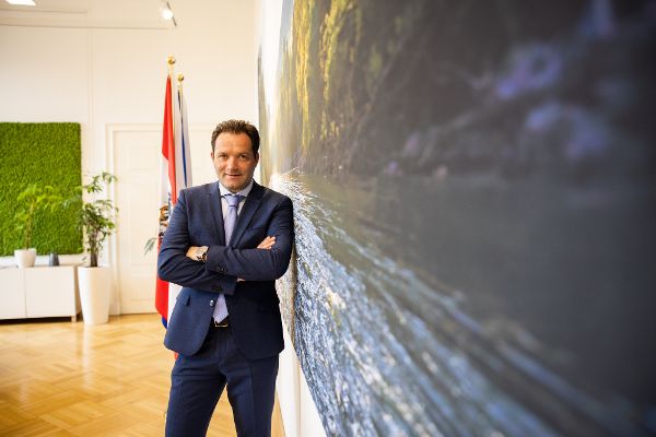 Landwirtschaftsminister Mag. Norbert Totschnig steht mit den Armen verschränkt an eine Wand gelehnt