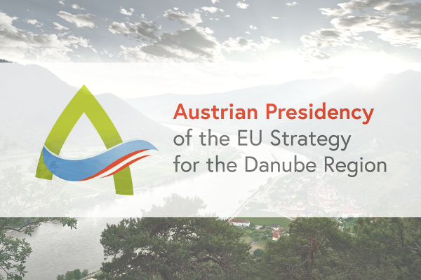 Austrian Presidency of the EU Strategy for the Danube Region Logo, im Hintergrund die Donau mit Bergen