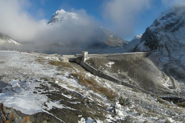 Sperrenmauer Spullersee, im Hintergrund beschneite Berge teilweise im Nebel