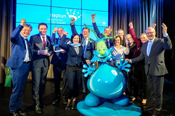 Die Siegerinnen und Sieger des Neptun Hauptpreises stehen mit  einer Wassertropfenfigur auf der Bühne und freuen sich über die Auszeichnung